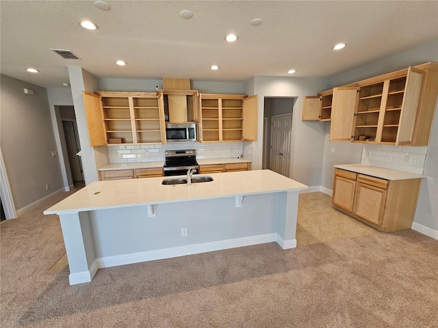 kitchen featuring a kitchen bar, sink, light carpet, an island with sink, and stainless steel appliances