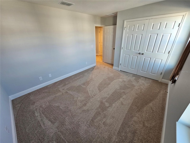 unfurnished bedroom featuring light carpet and a closet