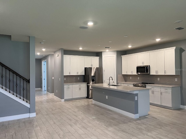 4535 Gliding Wave St, Winter Garden, FL 34787 - kitchen featuring white cabinetry, an island with sink, sink, stainless steel appliances, and light wood-type flooring