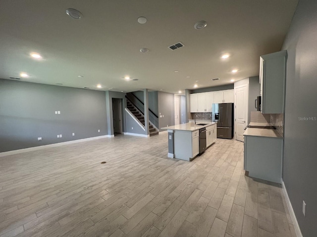 4535 Gliding Wave St, Winter Garden, FL 34787 - kitchen featuring sink, backsplash, light hardwood / wood-style floors, black appliances, and an island with sink
