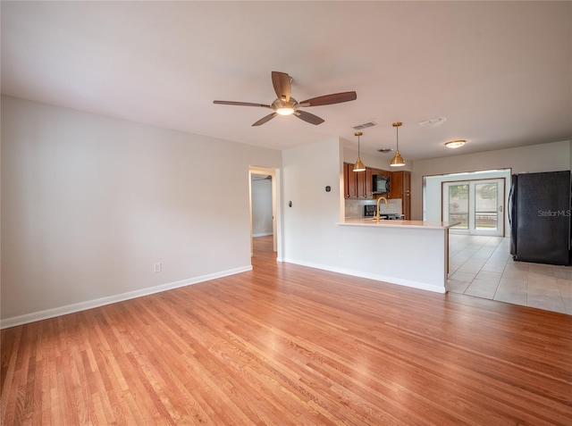 unfurnished living room featuring light wood-type flooring, ceiling fan, and sink