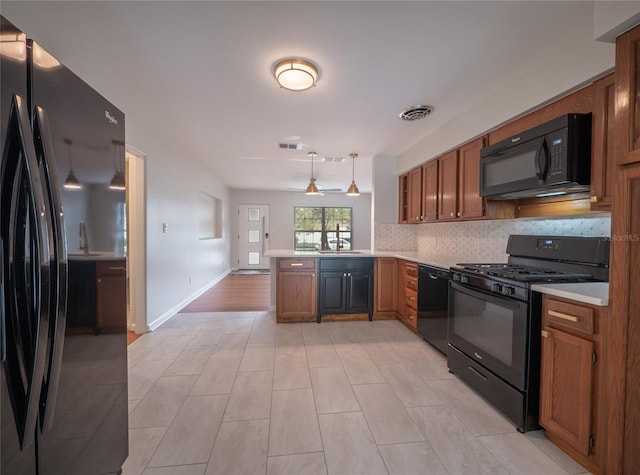 kitchen with pendant lighting, black appliances, sink, decorative backsplash, and kitchen peninsula