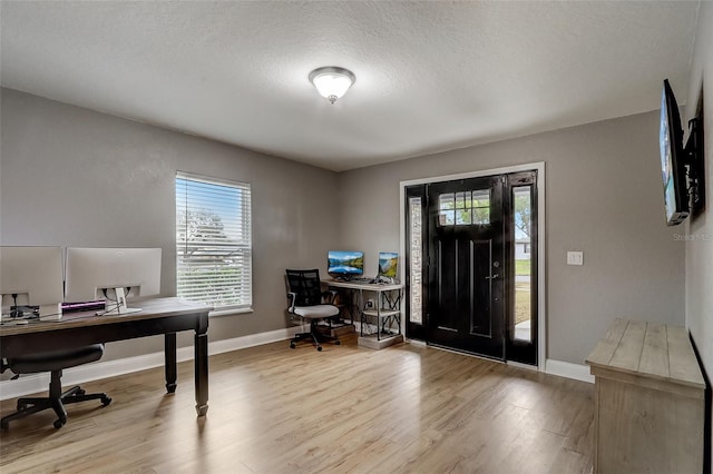 office with light wood-type flooring and a textured ceiling