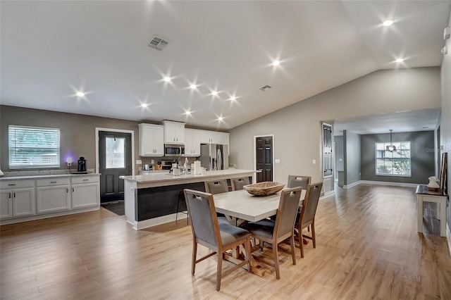 dining space with plenty of natural light, lofted ceiling, and light wood-type flooring