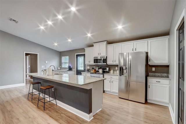 kitchen featuring white cabinets, appliances with stainless steel finishes, light wood-type flooring, and a kitchen island with sink