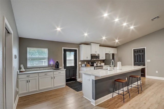 kitchen featuring light hardwood / wood-style floors, white cabinetry, a kitchen island with sink, and stainless steel appliances