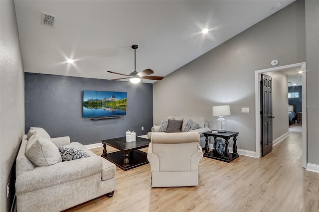 living room featuring light hardwood / wood-style floors, vaulted ceiling, and ceiling fan