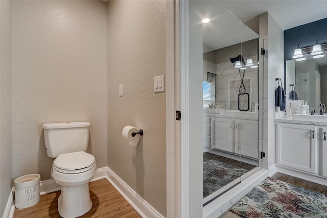 bathroom with hardwood / wood-style floors, vanity, toilet, and walk in shower