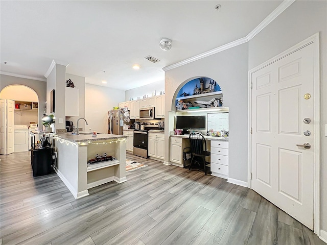 kitchen with crown molding, washing machine and clothes dryer, appliances with stainless steel finishes, and light hardwood / wood-style floors