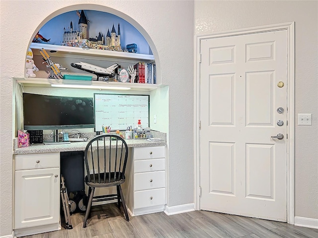 office space featuring built in desk and light hardwood / wood-style flooring