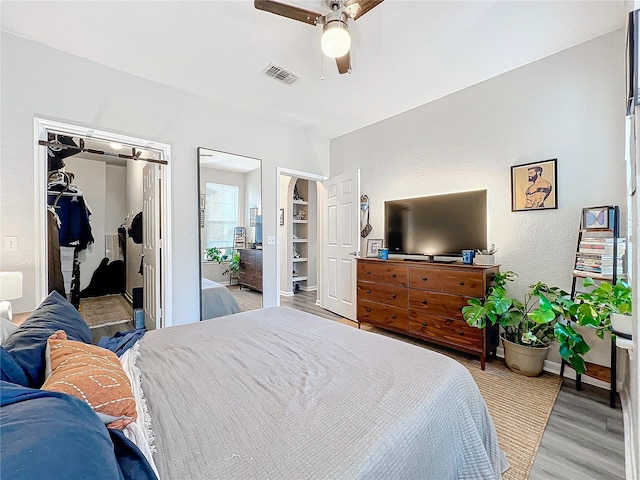 bedroom with a closet, a walk in closet, ceiling fan, and light hardwood / wood-style flooring