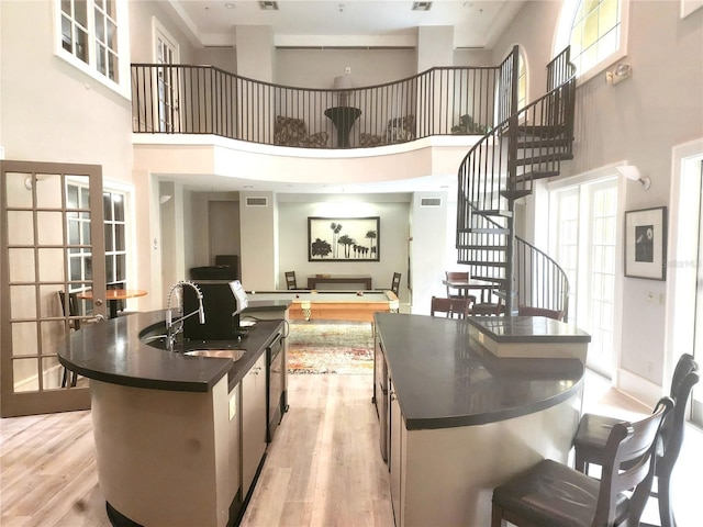 interior space featuring sink, light wood-type flooring, french doors, and a center island with sink