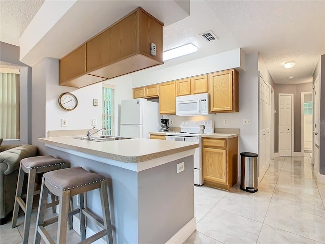 kitchen featuring a textured ceiling, sink, white appliances, and kitchen peninsula