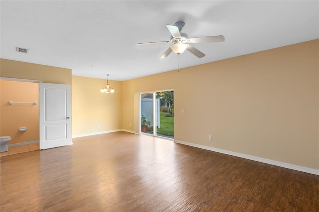 empty room featuring ceiling fan with notable chandelier and hardwood / wood-style flooring