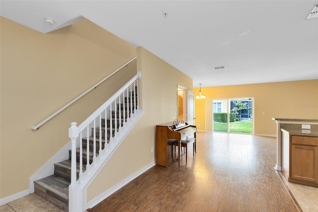 staircase with hardwood / wood-style floors and an inviting chandelier