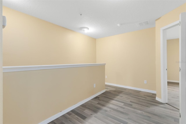 spare room featuring a textured ceiling and light hardwood / wood-style flooring