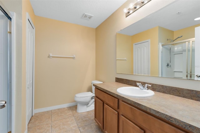 bathroom with tile patterned floors, an enclosed shower, a textured ceiling, vanity, and toilet