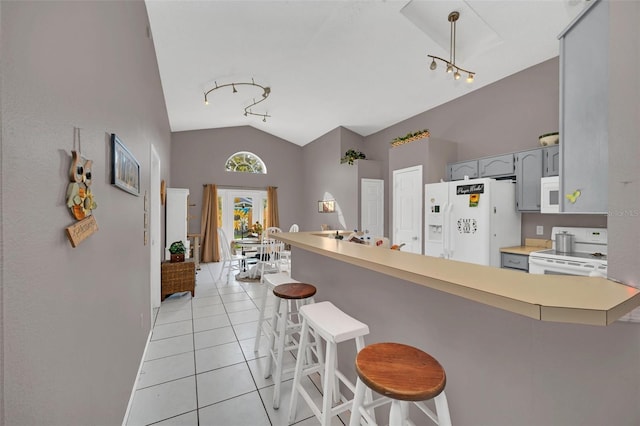 kitchen featuring gray cabinetry, kitchen peninsula, lofted ceiling, white appliances, and a breakfast bar area