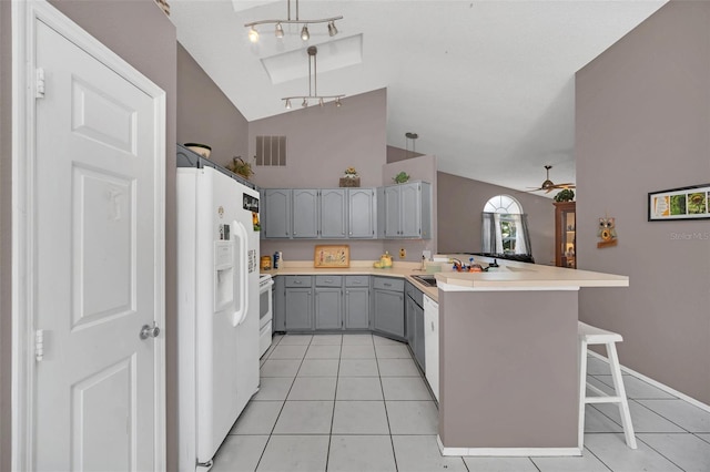 kitchen featuring ceiling fan, kitchen peninsula, lofted ceiling, white appliances, and a kitchen bar