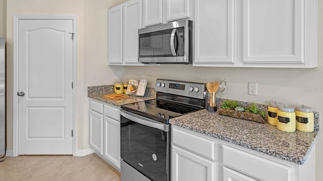 kitchen featuring light stone countertops, white cabinets, stainless steel appliances, and light tile patterned floors