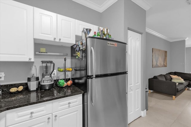 kitchen featuring white cabinetry, stainless steel refrigerator, crown molding, and dark stone countertops