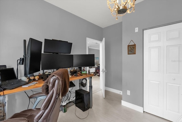 home office featuring light wood-type flooring and a notable chandelier