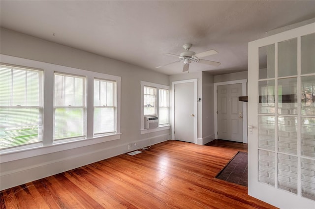 spare room featuring wood-type flooring, ceiling fan, cooling unit, and a wealth of natural light