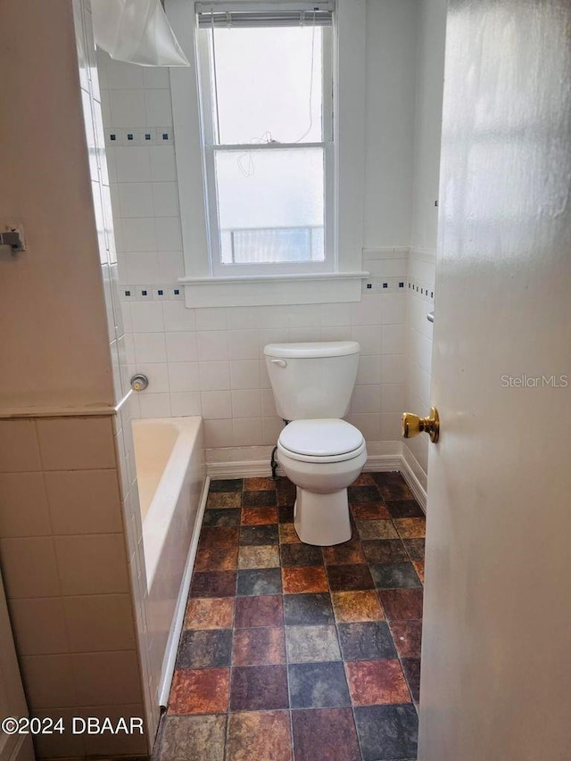 bathroom with tile walls, toilet, and a bath