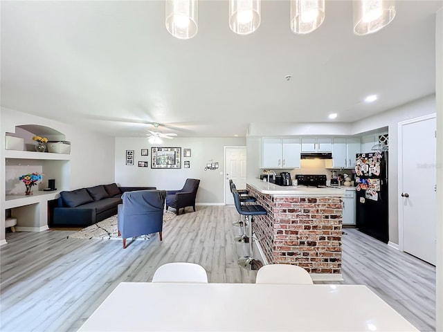 interior space with ceiling fan, black appliances, pendant lighting, built in features, and white cabinets