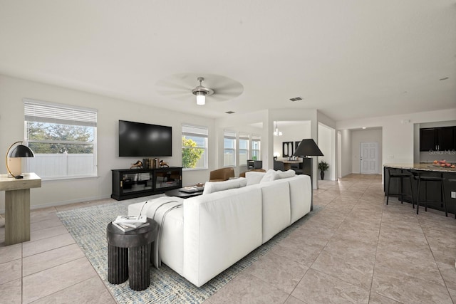 tiled living room with plenty of natural light and ceiling fan with notable chandelier