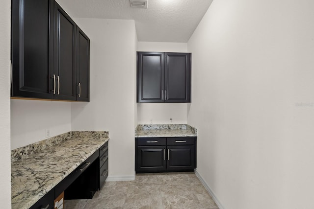 kitchen with light stone countertops and a textured ceiling