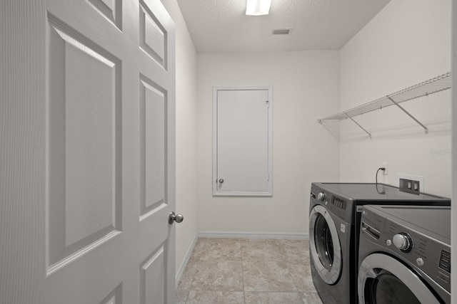 washroom with a textured ceiling and washing machine and clothes dryer