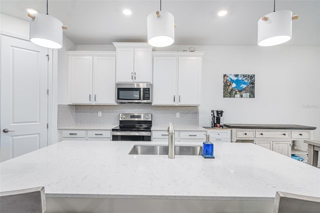 kitchen featuring sink, appliances with stainless steel finishes, white cabinetry, backsplash, and decorative light fixtures