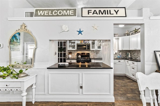 kitchen with white cabinets, dark hardwood / wood-style floors, black range with gas stovetop, and backsplash