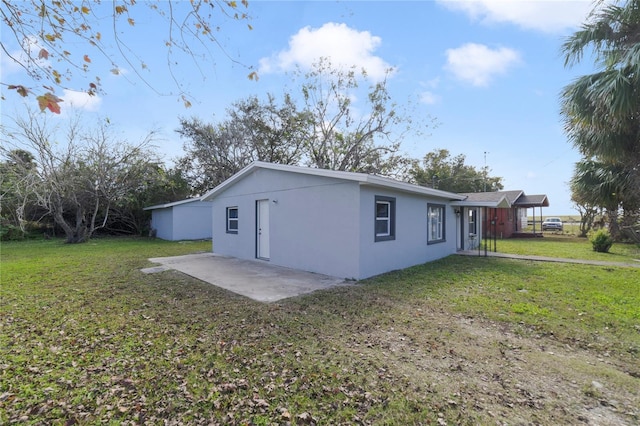 view of side of property with a patio area and a lawn