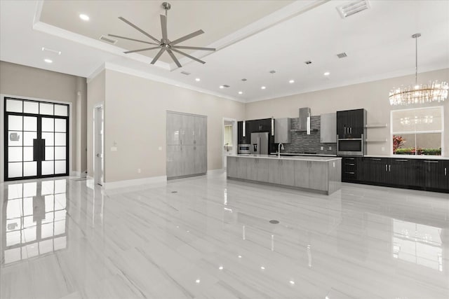 kitchen with open floor plan, modern cabinets, wall chimney range hood, a large island with sink, and appliances with stainless steel finishes