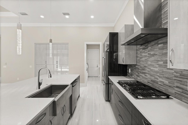 kitchen with pendant lighting, wall chimney range hood, light countertops, appliances with stainless steel finishes, and backsplash