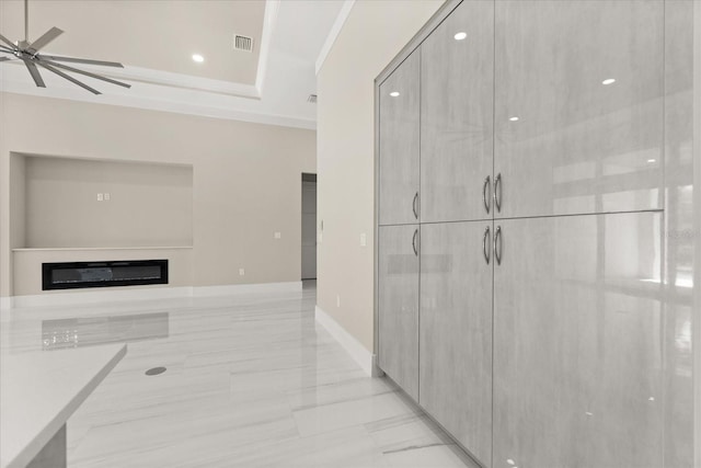 hall with a raised ceiling, recessed lighting, visible vents, and marble finish floor