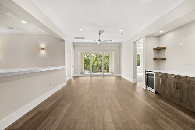 unfurnished living room featuring crown molding, dark wood-style flooring, ceiling fan, beverage cooler, and baseboards