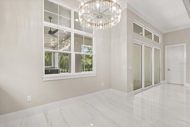 empty room featuring baseboards, a notable chandelier, marble finish floor, and a towering ceiling