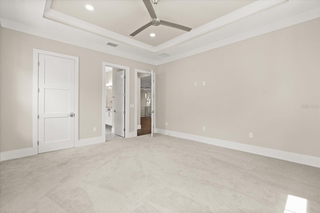 unfurnished bedroom with light carpet, baseboards, ensuite bathroom, recessed lighting, and a tray ceiling