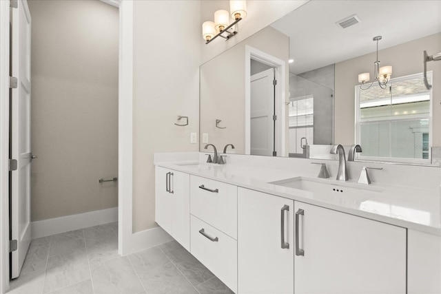 bathroom with an inviting chandelier, a sink, marble finish floor, and a stall shower