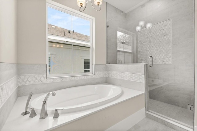 bathroom featuring an inviting chandelier, a shower stall, and a bath