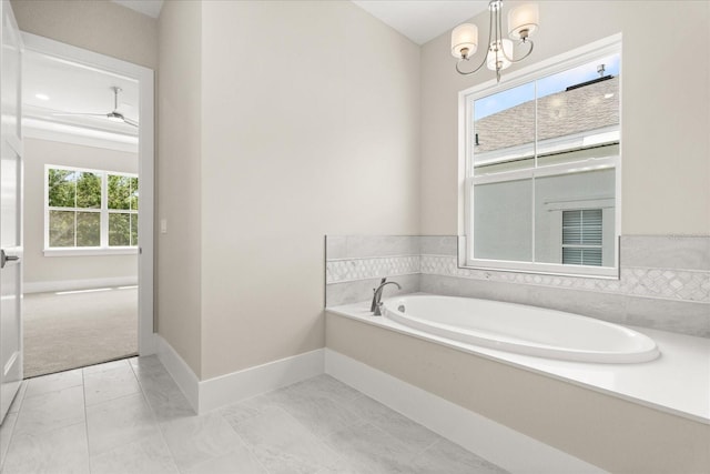 bathroom featuring baseboards, a bath, and ceiling fan with notable chandelier