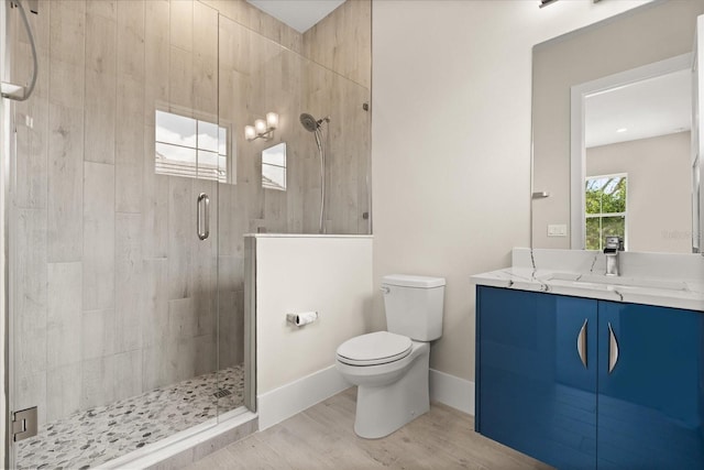 bathroom with wood finished floors, a stall shower, toilet, and vanity