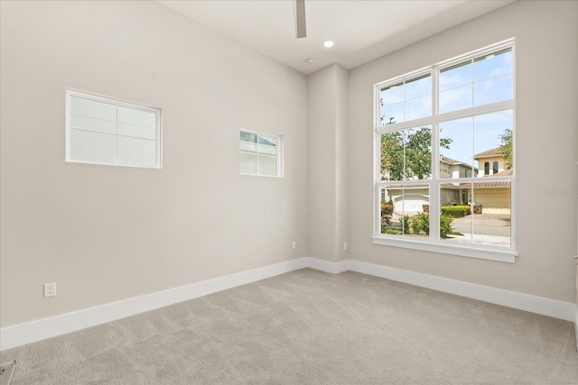 carpeted spare room featuring baseboards, ceiling fan, and a healthy amount of sunlight
