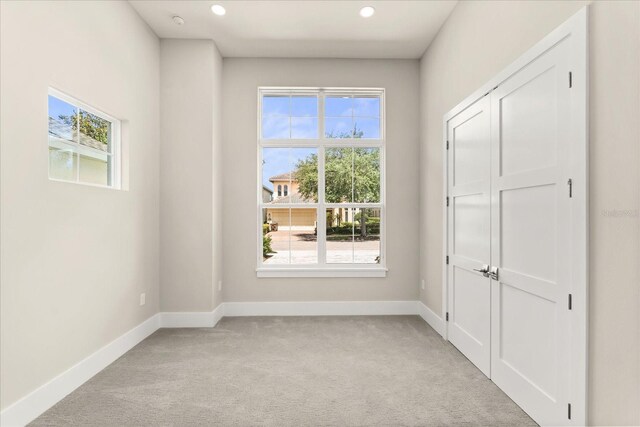 empty room featuring baseboards, recessed lighting, and light carpet