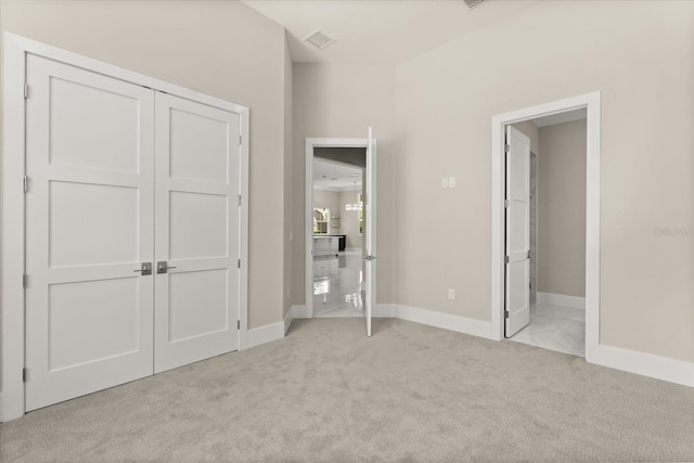 unfurnished bedroom featuring connected bathroom, baseboards, visible vents, and light carpet