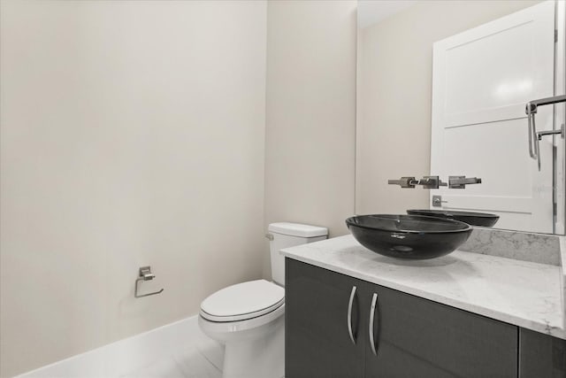 bathroom featuring toilet, baseboards, and vanity
