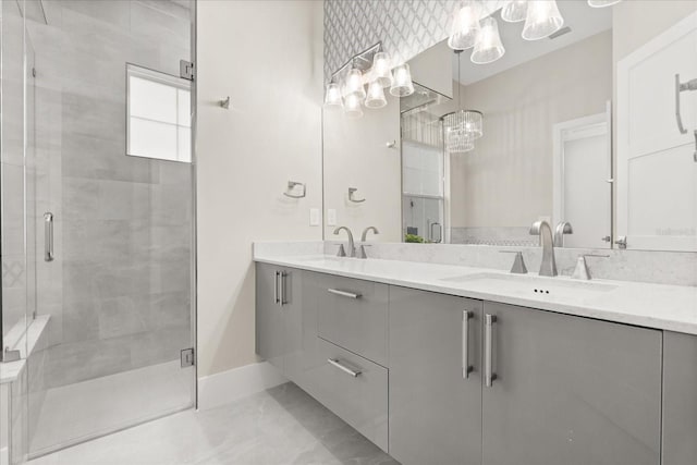 full bathroom with a sink, baseboards, a stall shower, and a chandelier